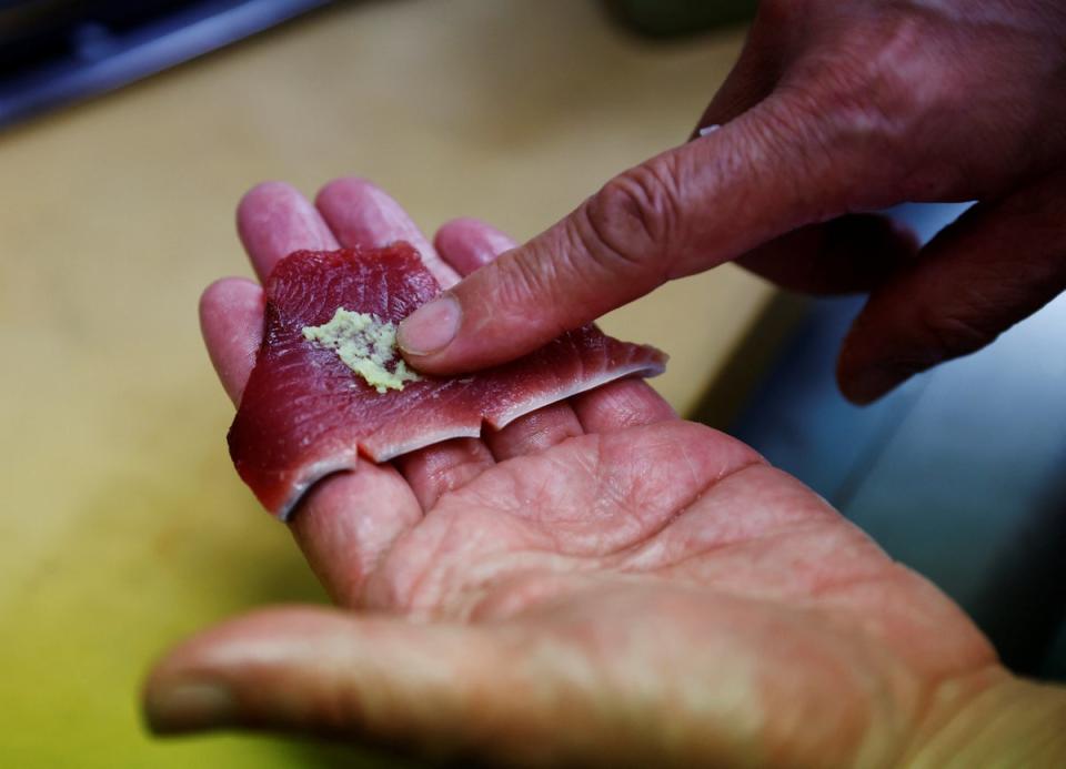 Noriaki Ito, head chef of 106 year-old restaurant Tsukasa, puts wasabi on a piece of raw katsuo (skipjack tuna), in Kochi (Reuters)