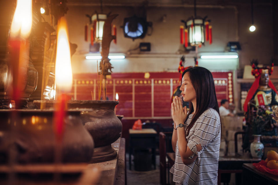 Young Asian female put her palms together praying sincerely and devoutly in a temple.