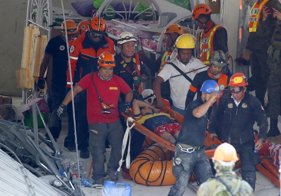 In this April 23, 2019, file photo, rescuers carry an earthquake survivor after being pulled out from the rubble of a commercial building following a 6.1 magnitude earthquake in Porac township, Pampanga province, north of Manila, Philippines. (AP Photo/Bullit Marquez, File)