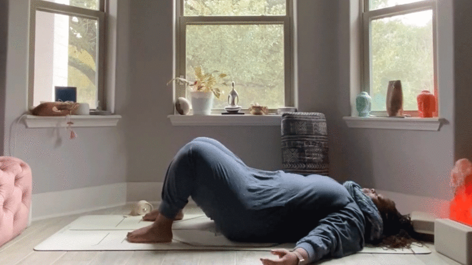 Woman stretching her low back in her bedroom