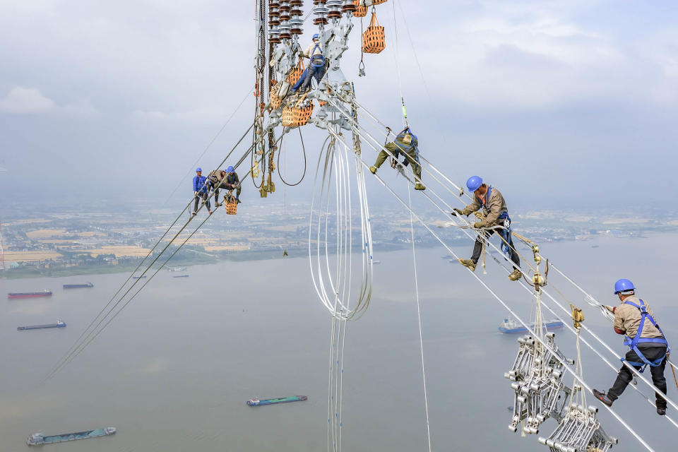 2022年6月1日，江蘇省泰州市，工人們在長江沿岸的輸電塔上安裝電線。