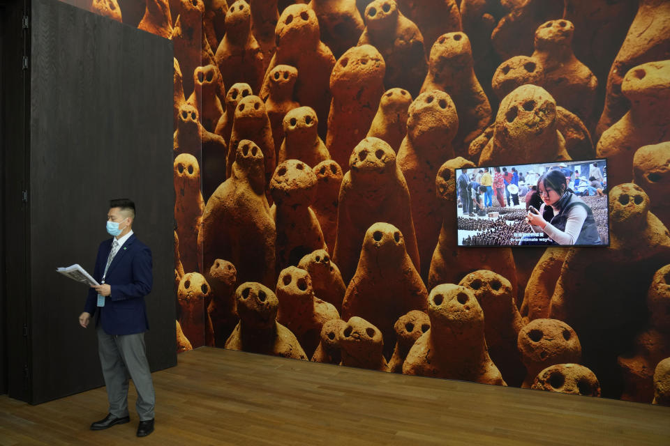 A man stands in front of a poster of an installation titled "Asian Field", designed by British artist Antony Gormley, during a media preview inside the "M+" visual culture museum in the West Kowloon Cultural District of Hong Kong, Thursday, Nov. 11, 2021. Hong Kong's swanky new M+ museum _ Asia's largest gallery with a billion-dollar collection _ is set to open on Friday amid controversy over politics and censorship. (AP Photo/Kin Cheung)