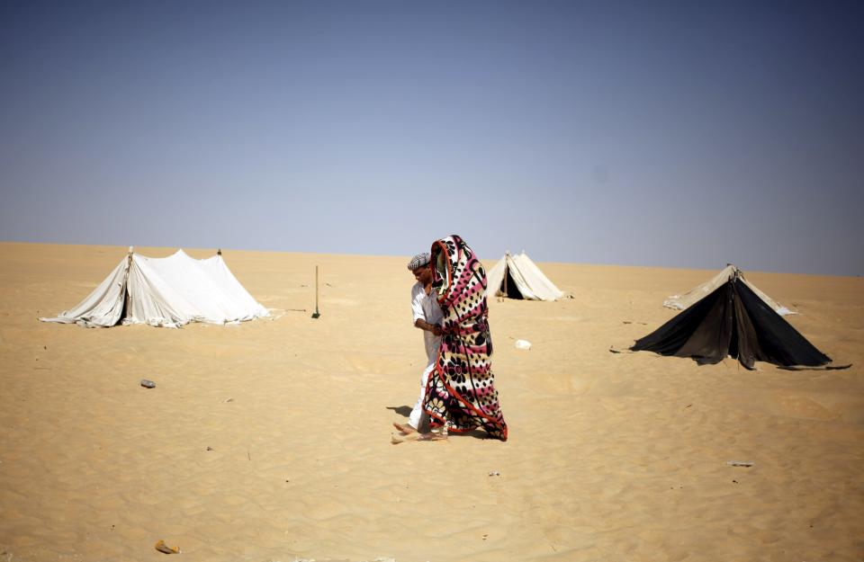 A worker helps a patient, who is wrapped in a blanket leave, a "sauna" tent after his sand bath in Siwa, Egypt, August 12, 2015. (REUTERS/Asmaa Waguih)