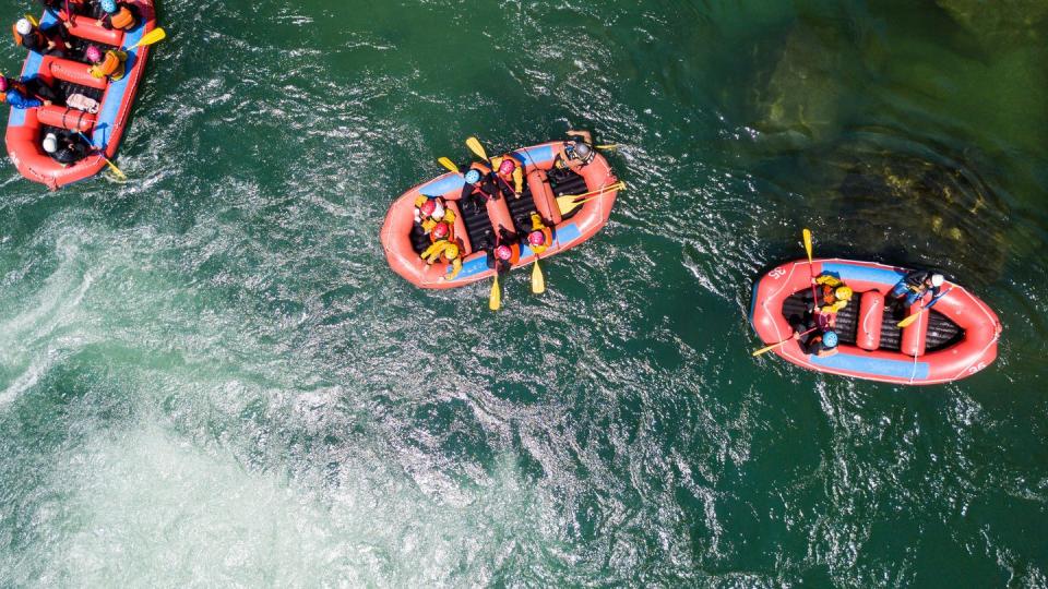 aerial view of a group of men and women in multiple boats white water river rafting