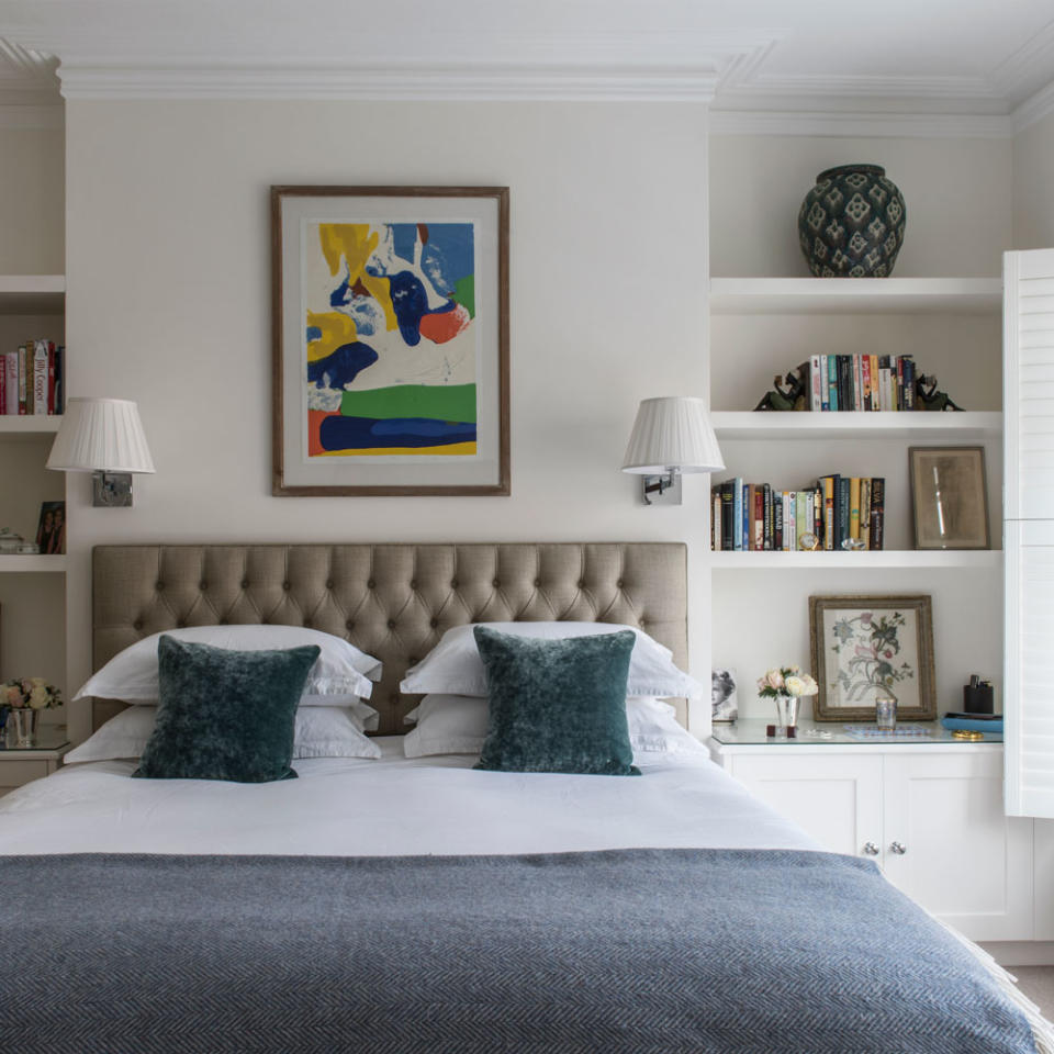 Bedroom with double bed, headboard, wall lamps and shelving alcoves
