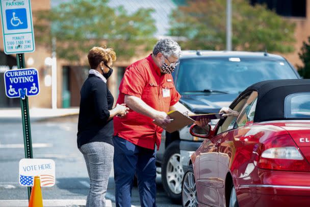 PHOTO: Election workers Tim McLeod and Cybil Usual assist a voter casting their ballot curbside on the first day of early voting at the Office of Elections satellite location at Southpoint in Spotsylvania, Va., Sept. 18, 2020. (Mike Morones/The Free Lance-Star via AP, FILE)