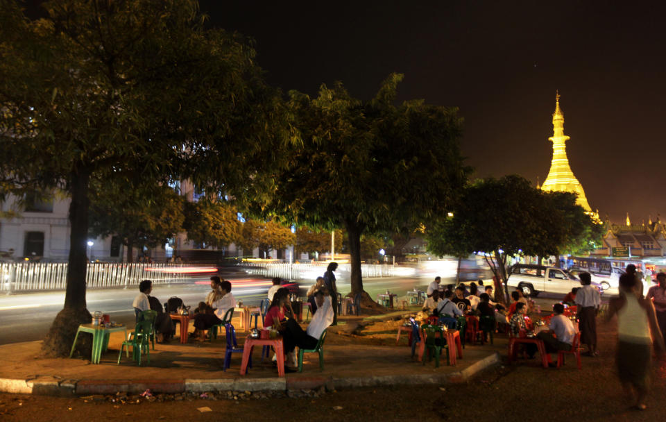 In this photo taken Feb. 25, 2012, people dine in open at an empty parking space near Sule Pagoda in Yangon, Myanmar. Now that Myanmar is opening to the outside world, good luck getting a room. For now, Myanmar is the sort of time-warped place that adventurous travelers love. There are no Starbucks or McDonald's or name-brand Western hotels, but some of that will soon change. (AP Photo/Altaf Qadri)