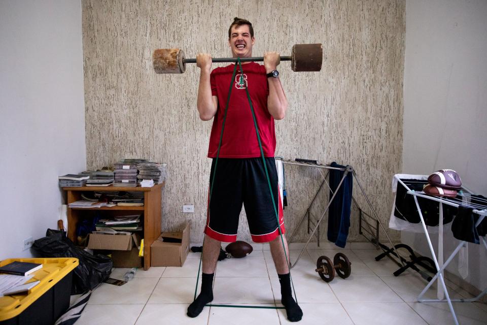 Elder Tanner McKee, a missionary for The Church of Jesus Christ of Latter-day Saints, works out in his home in Paranaguá, Brazil, on Monday, June 3, 2019. McKee has had to be creative to keep up his workout regimen while on his mission. Here, he uses a makeshift barbell with blocks of concrete on each end, plus a resistance band under his feet. | Spenser Heaps, Deseret News