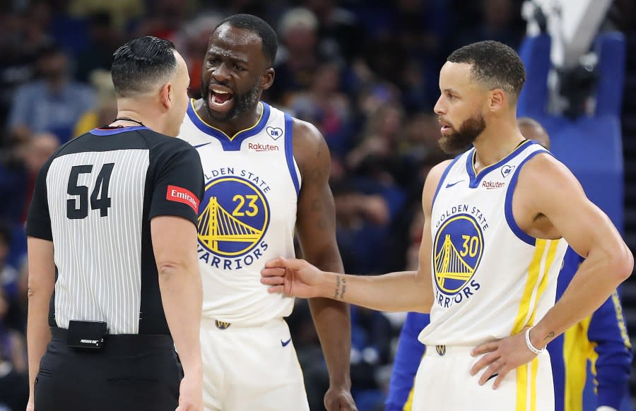 The Golden State Warriors’ Draymond Green (23) screams at game official Ray Acosta (54) as teammate Stephen Curry (30) steps in at right during action against the Orlando Magic at the Kia Center on Wednesday, March 27, 2024, in Orlando, Florida. (Stephen M. Dowell/Orlando Sentinel/Tribune News Service via Getty Images)