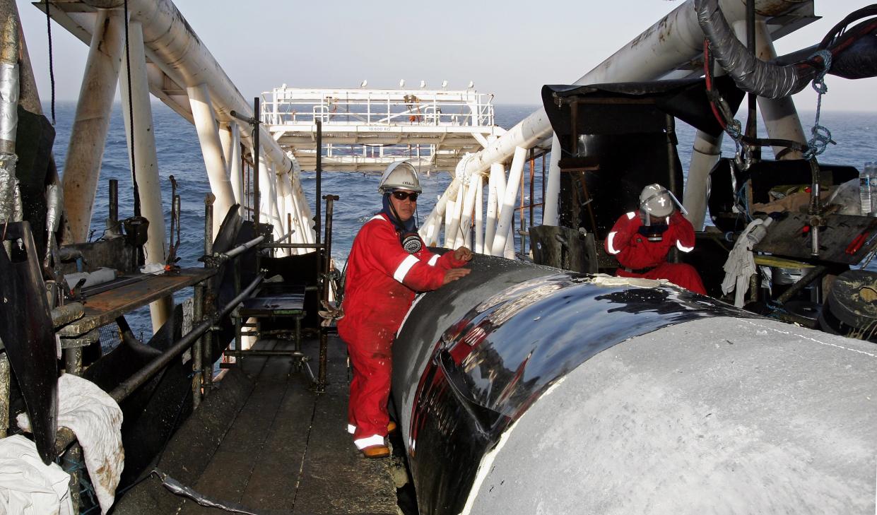 BERGEN, NORWAY - SEPTEMBER 21:  Workers make final preparations to pipes as they enter the sea from the pipelay vessel Acergy Piper on September 21, 2006 in Bergen, Norway. The Acergy Piper is one of the world?s most efficient semi-submersible pipelay barges. She is currently laying the world's longest trunkline between Norway and England. Langeled trunkline is 1200km long, 44