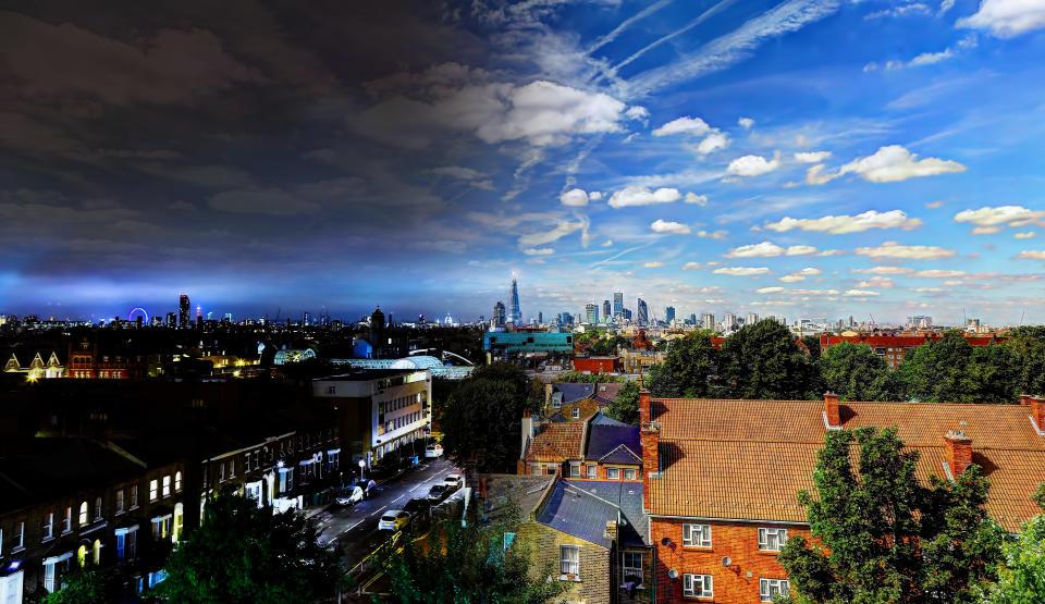 Two images of central London from a rooftop merged together to show the transition from night to day in a single image.