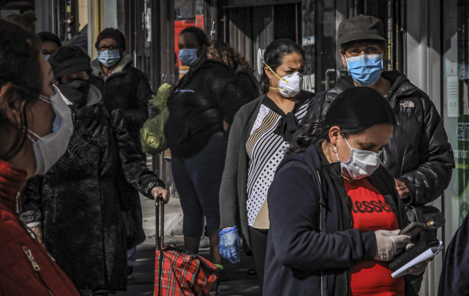 Women in Brooklyn's Sunset Park, a neighborhood with one of the city's largest Mexican and Hispanic community, wear masks to help stop the spread of coronavirus while waiting in line to enter a store, Tuesday May 5, 2020, in New York. A poll found that 61% of Hispanic Americans say they've experienced some kind of household income loss as a result of the COVID-19 outbreak. (AP Photo/Bebeto Matthews)