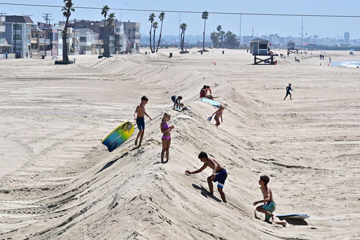 Children make their way up and down a sand berm put in place to protect low-lying beachfront homes in Seal Beach, California on August 18, 2023, as they prepare for hurricane Hilary. (AFP via Getty Images)