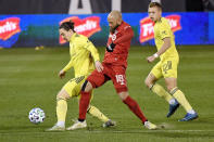 Toronto FC's Nick DeLeon, center, challenges Nashville SC's Alex Muyl, left, as Nashville's Alistair Johnston watches during the first half of an MLS soccer playoff match Tuesday, Nov. 24, 2020, in East Hartford, Conn. (AP Photo/Jessica Hill)