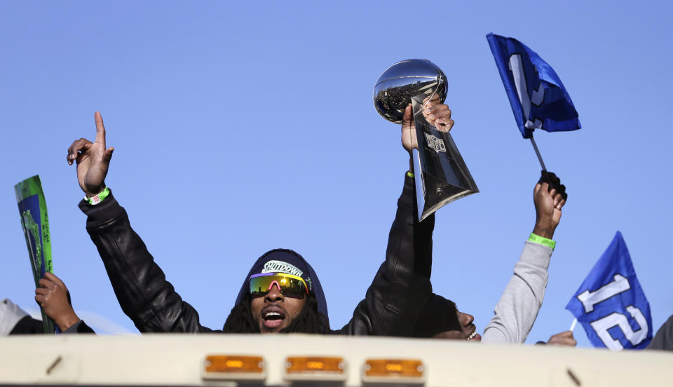 Seattle Seahawks' Richard Sherman holds up the Vince Lombardi Trophy during a parade for the NFL football Super Bowl champions Wednesday, Feb. 5, 2014, in Seattle. The Seahawks defeated the Denver Broncos 43-8 on Sunday. (AP Photo/Elaine Thompson)