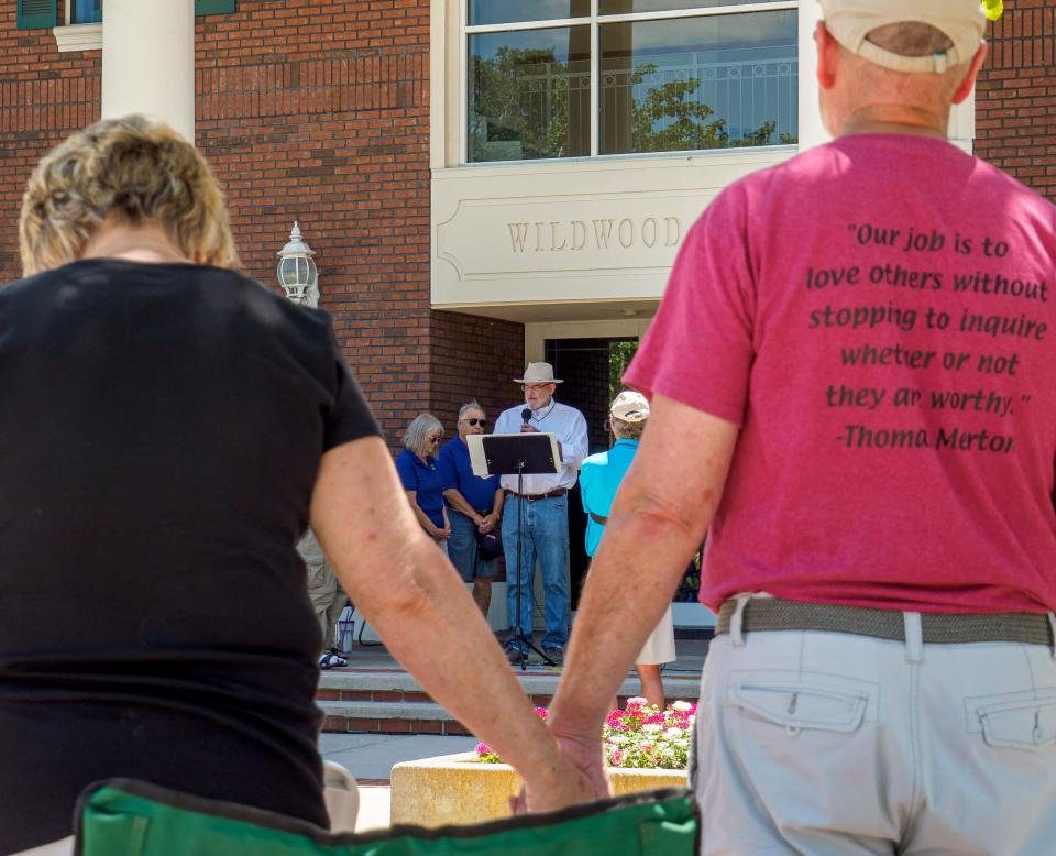 A couple holds hands as the names of mass shooting victims are read aloud during an interfaith prayer vigil held in the aftermath of recent mass shootings in Wildwood on Saturday, May 28, 2022. [PAUL RYAN / CORRESPONDENT]