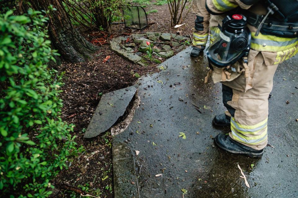 Firefighters from Dover inspect a portion of driveway after a lightning strike charred trees and caused a partial collapse to the chimney of Ben and Nancy Cox's home on Columbia Road NW, Wednesday, April 17 in Franklin TWP.