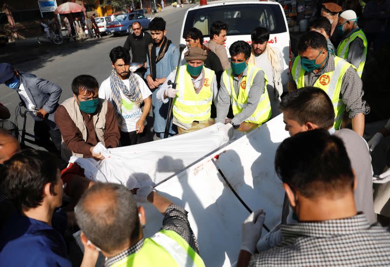 Afghan men carry an injured to a hospital after a blast in Kabul, Afghanistan