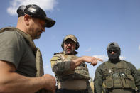 Belarus regiment leader, Vadim Prokopiev, left, Polish instructor, Dariusz Tomysek, center, and a volunteer from Belarus speak during a training session at a shooting range near Warsaw, Poland, on Friday, May 20, 2022. (AP Photo/Michal Dyjuk)