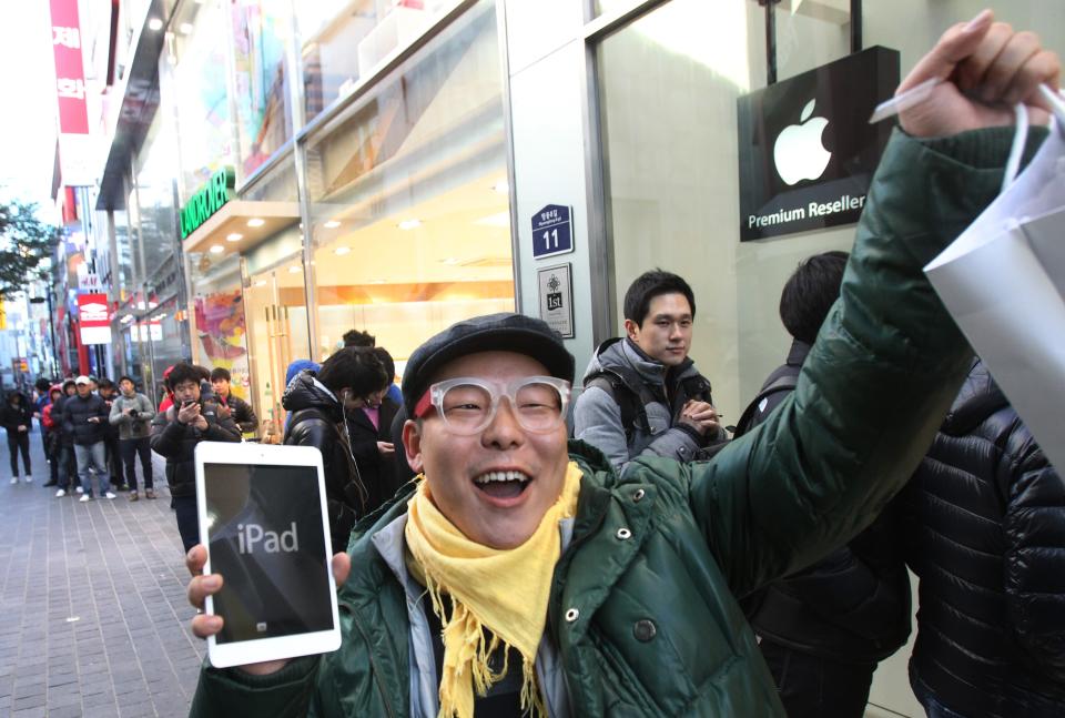 FILE -In this Friday, Nov. 2, 2012, file photo, a customer, Song Tae-min reacts after buying a new iPad Mini in Seoul, South Korea. The tablet computer is without a doubt the gift of the year. just like it was last year. But if you resisted the urge in 2011, now is the time to give in. This season's tablets are better all around. Intense competition has kept prices very low, making tablets incredible values compared to smartphones and PCs (AP Photo/Ahn Young-joon)