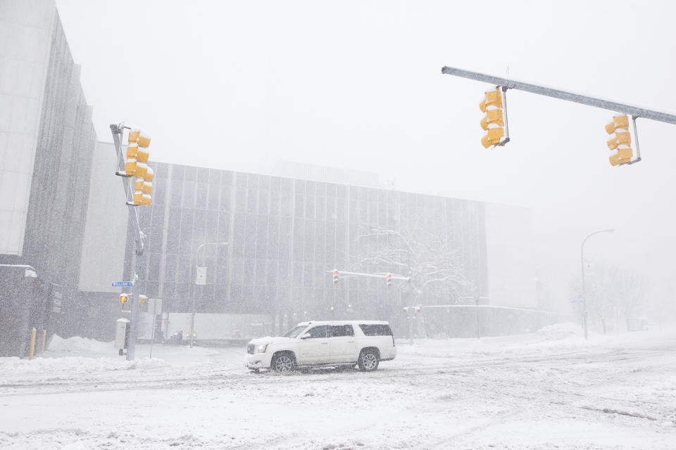 A car drives by the Buffalo and Erie County Public Library as snow falls Friday, Nov. 18, 2022, in Buffalo, N.Y. A dangerous lake-effect snowstorm paralyzed parts of western and northern New York, with nearly 2 feet of snow already on the ground in some places and possibly much more on the way. (AP Photo/Joshua Bessex)