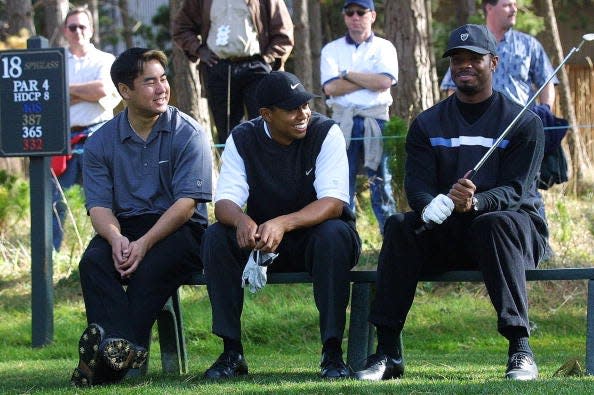 Tiger Woods (C) speaks with Ken Griffey Jr. (R) and Woods' Stanford University college friend Jerry Chang at the 18th hole at Spyglass course during the first round of the AT&T Pebble Beach National Pro-Am Golf in Pebble Beach, California on Feb. 1, 2001.