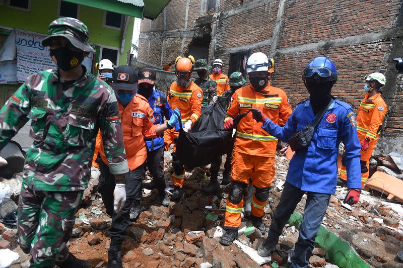 Rescue workers carry bag with body of victim following earthquake in Mamuju, West Sulawesi