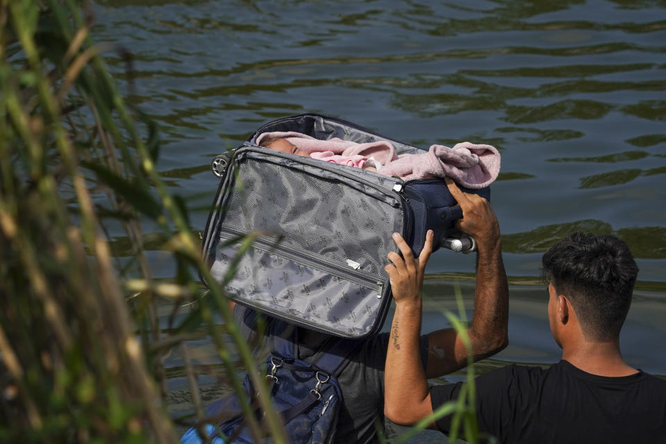 A migrant crosses the Rio Grande river with a baby in a suitcase, as seen from Matamoros, Mexico, Wednesday, May 10, 2023. The U.S. on May 11 will begin denying asylum to migrants who show up at the U.S.-Mexico border without first applying online or seeking protection in a country they passed through, according to a new rule released on May 10. (AP Photo/Fernando Llano)