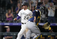 Colorado Rockies' Ryan McMahon, back, crosses home plate to score the winning run as Milwaukee Brewers catcher Omar Narvaez looks for the throw during the 10th inning of a baseball game Friday, June 18, 2021, in Denver. The Rockies won 6-5. (AP Photo/David Zalubowski)