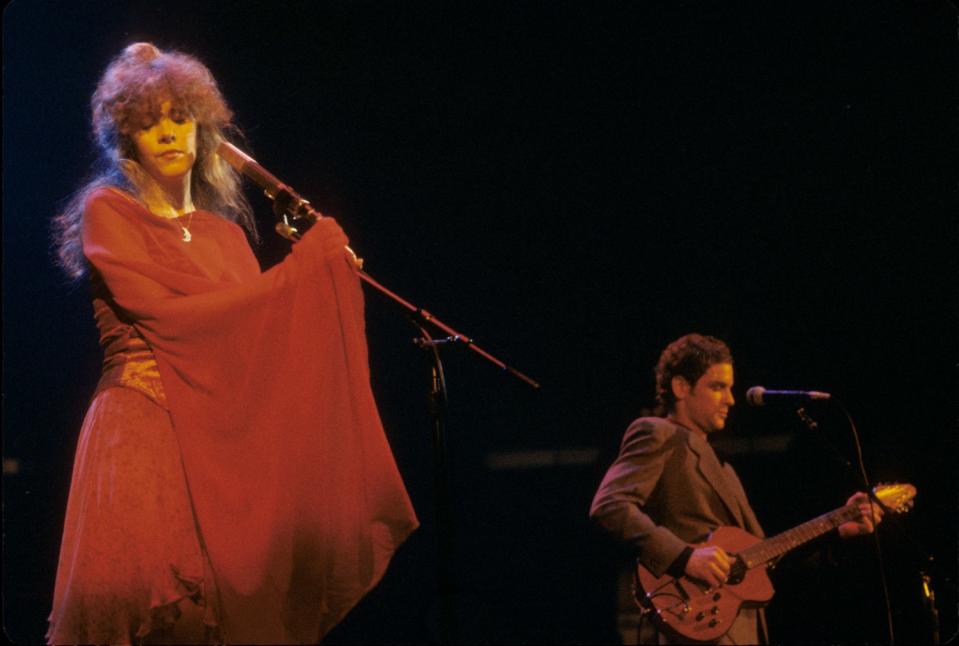 A woman in a red dress sings with a man playing guitar