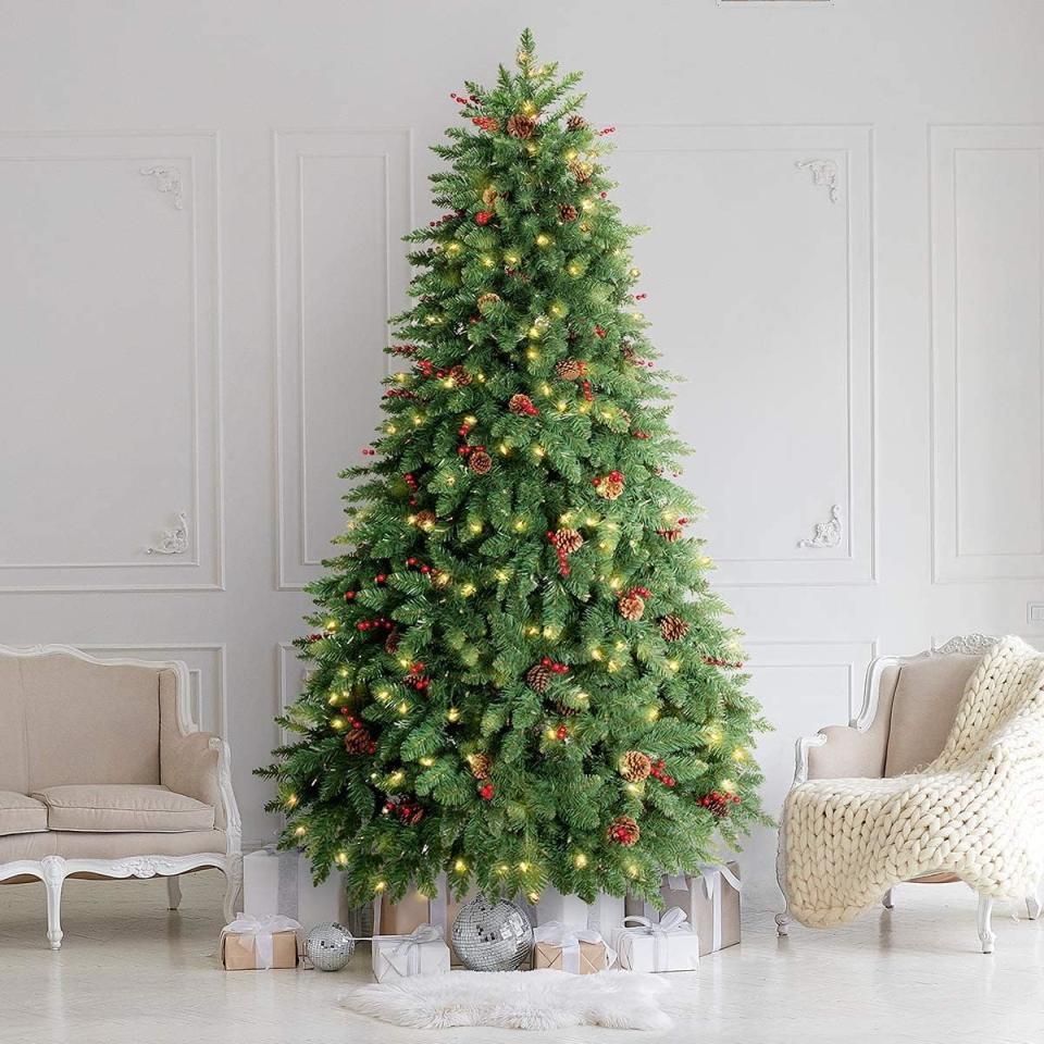 pre-lit fake christmas tree with berries and pinecones next to two chairs