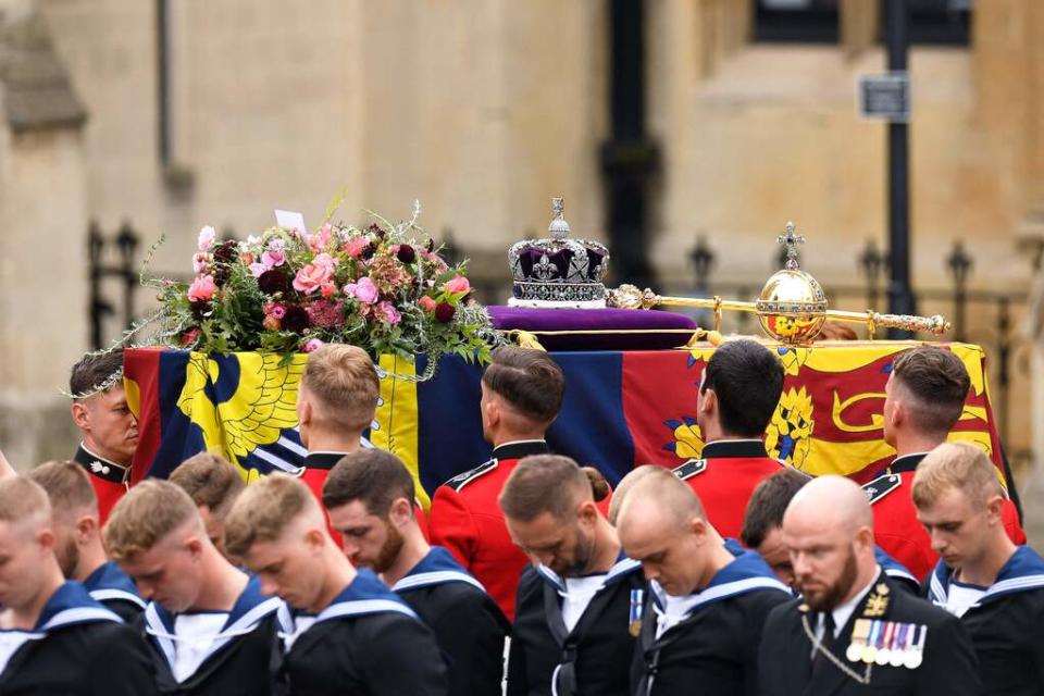 The coffin of Queen Elizabeth II, draped in a Royal Standard and adorned with the Imperial State Crown and the Sovereign's orb and sceptre is taken into Westminster Abbey during the State Funeral Service for Britain's Queen Elizabeth II, in London on September 19, 2022.