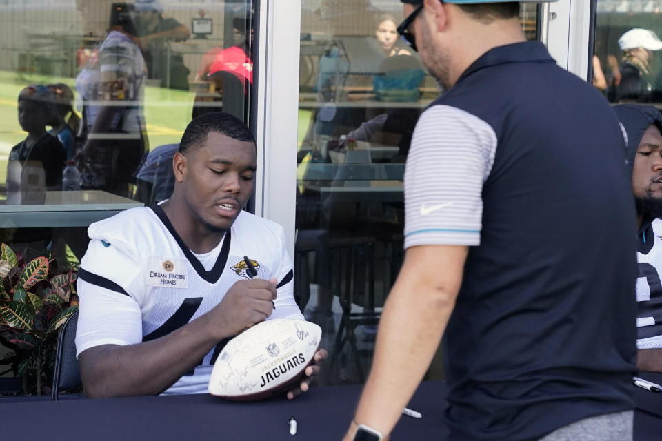 Jacksonville Jaguars linebacker Travon Walker (44) signs autographs for fans after a practice at the NFL football team's training camp, Saturday, July 29, 2023, in Jacksonville, Fla. (AP Photo/John Raoux)