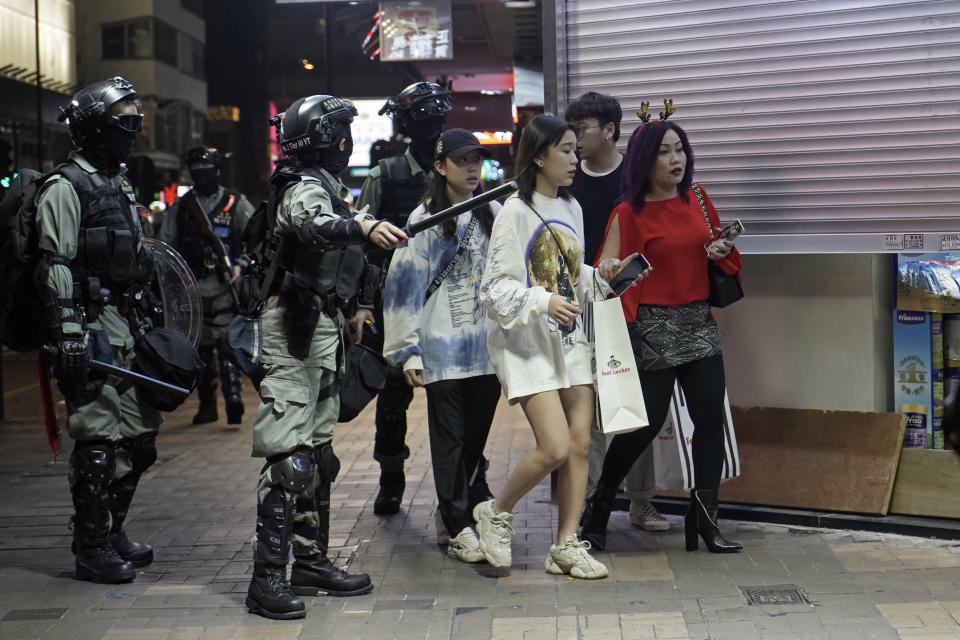 Police guide tourists across the road as they prepare for action against protesters during a rally on Christmas Eve in Hong Kong, Tuesday, Dec. 24, 2019. More than six months of protests have beset the city with frequent confrontations between protesters and police. (AP Photo/Kin Cheung)