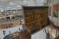 A protester holds a placard in a shopping mall during a protest against China's national security legislation for the city, in Hong Kong, Monday, June 1, 2020. The mouthpiece of China's ruling Communist Party says U.S. moves to end some trading privileges extended to Hong Kong grossly interfere in China's internal affairs and are doomed to fail. (AP Photo/Vincent Yu)