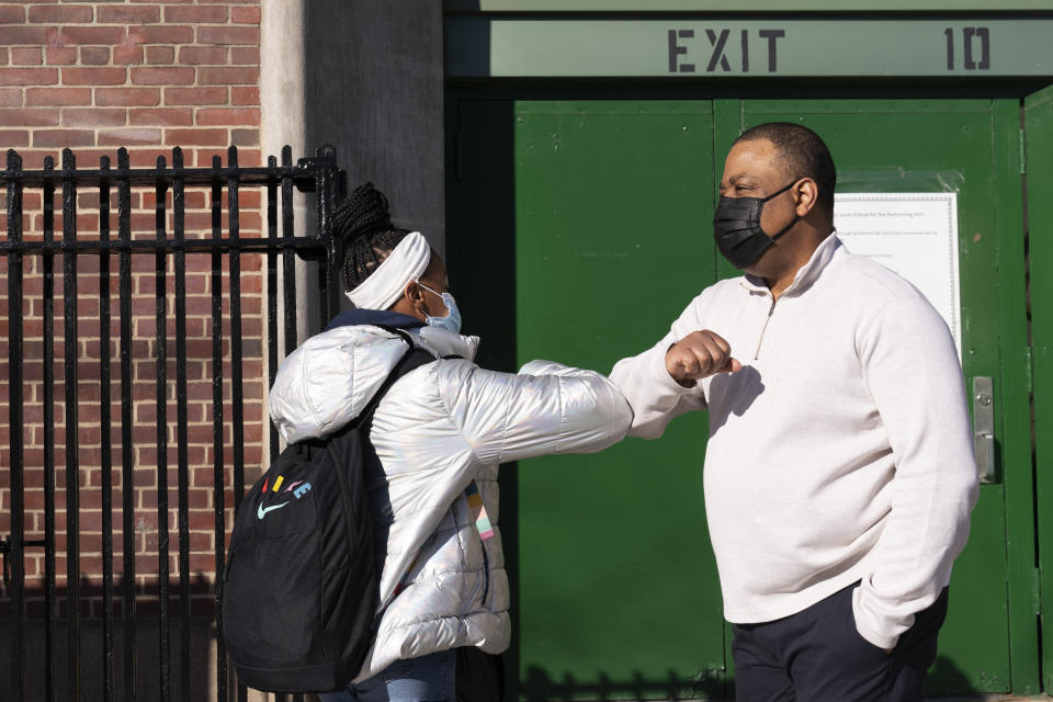 FILE - In this Feb. 25, 2021 file photo, Linsey Johnson, right, a dean at Meyer Levin Middle School, greets a student in New York. With COVID-19 cases soaring nationwide, school districts across the U.S. are yet again confronting the realities of a polarized country and the lingering pandemic as they navigate mask requirements, vaccine rules and social distancing requirements for the fast-approaching new school year. (AP Photo/Mark Lennihan, File)