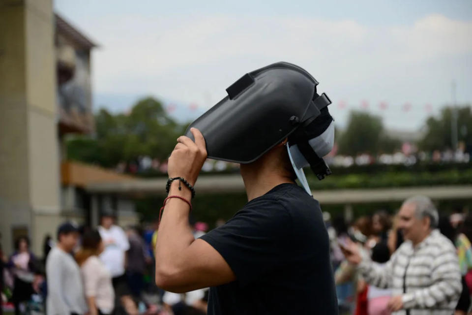 A man watches the Annular Solar Eclipse with a welding mask at the National Autonomous University of Mexico (UNAM)