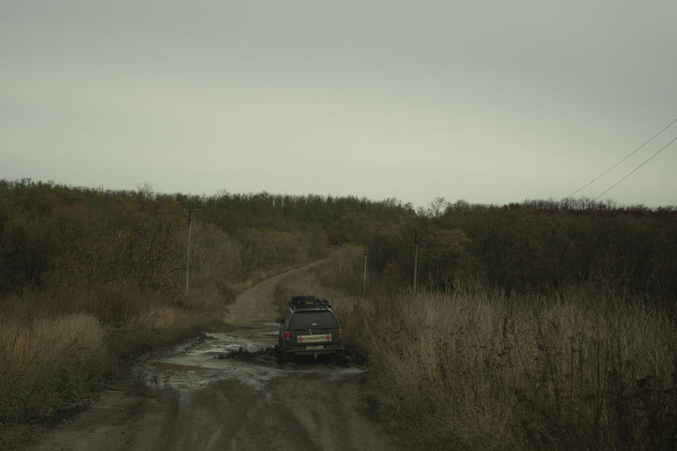 Oleksii Yukov and his team drive through a pothole on a road towards the frontline in Sloviansk region, Ukraine, Wednesday, Oct. 25, 2023. The 38-year-old martial arts instructor who leads a team of volunteer body collectors in Ukraine says he's collected over 1,000 bodies since the full-scale invasion began two years ago, more than 580 of them Russians. (AP Photo/Bram Janssen)