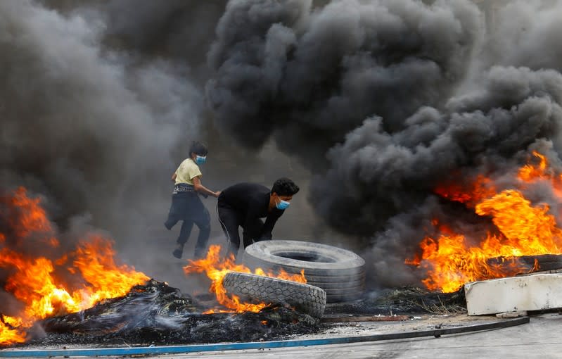 Iraqi demonstrators burn tires during the ongoing anti-government protests in Najaf