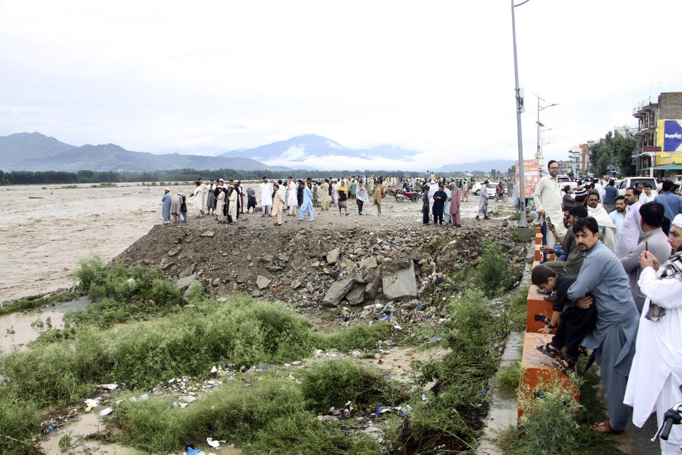 People stand at a bank of an overflowing stream in Mingora, the capital of Swat valley in Pakistan, Saturday, Aug. 27, 2022. Officials say flash floods triggered by heavy monsoon rains across much of Pakistan have killed nearly 1,000 people and displaced thousands more since mid-June. (AP Photo/Naveed Ali)