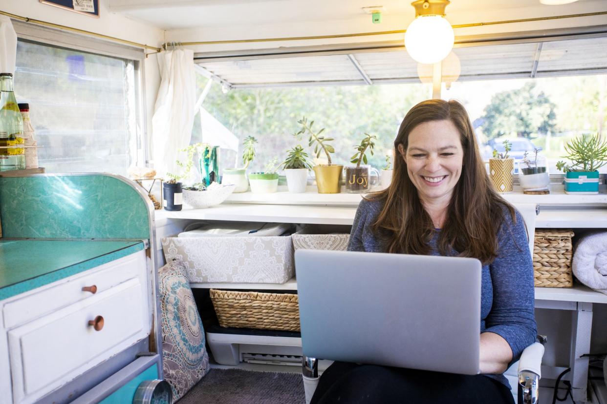woman smiling working from laptop in rv