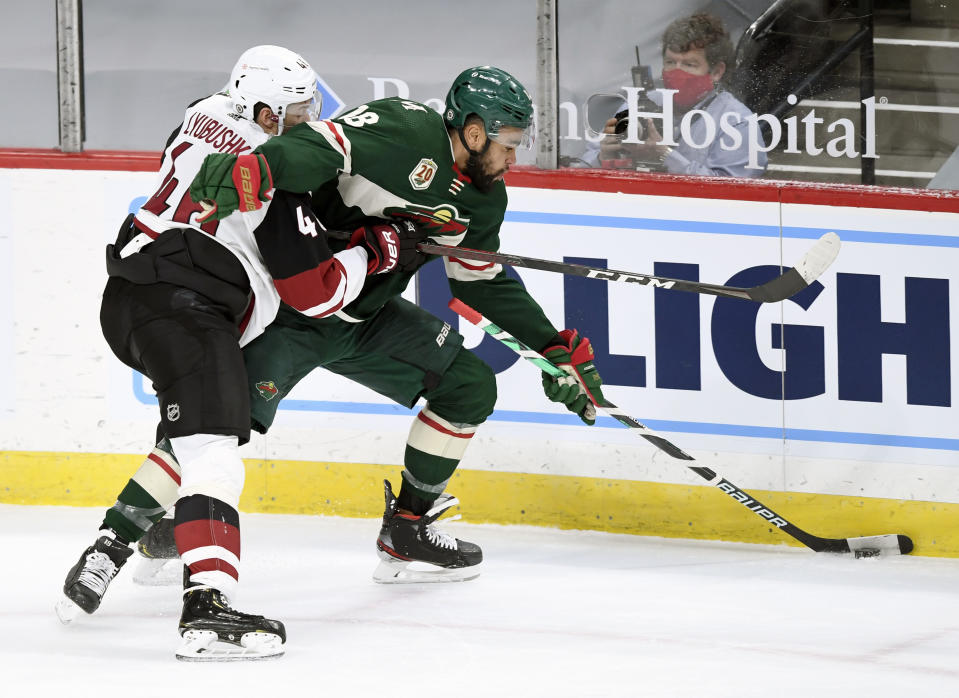 Minnesota Wild's Jordan Greenway (18) has the puck against Arizona Coyotes' Ilya Lyubushkin (46), of Russia, during the first period of an NHL hockey game Sunday, March 14, 2021, in St. Paul, Minn. (AP Photo/Hannah Foslien)