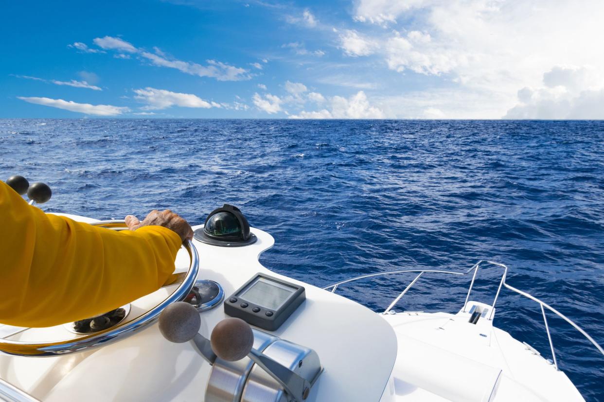 Hand of captain on steering wheel of motor boat in the blue ocean during the fishery day