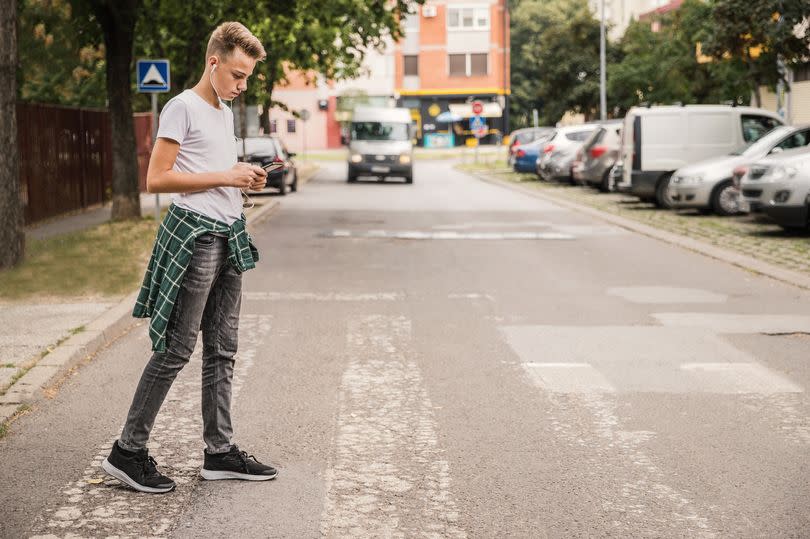 Schoolboy with mobile phone on pedestrian crossing going home