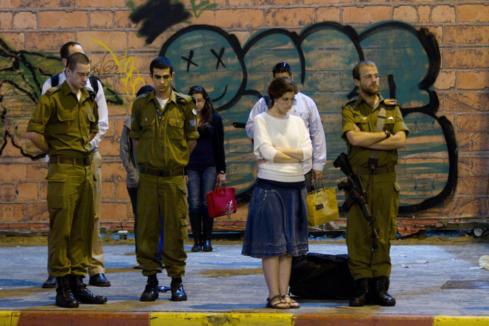 Israeli soldiers and civilians stand to observe a minute of silence as air raid sirens sounds in Tel Aviv to mark Israel's annual Memorial Day for soldiers and civilians killed in more than a century of conflict between Jews and Arabs in Tel Aviv, Israel,Tuesday, April 24, 2012. (AP Photo/Ariel Schalit)