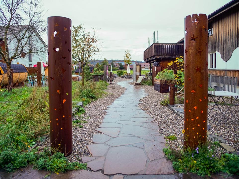 A stone pathway in a garden with cylindrical lanterns on each side