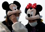 Visitors wearing protective face masks and Mickey and Minnie Mouse costumes, following an outbreak of the coronavirus, are seen outside Tokyo Disneyland in Urayasu