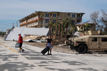 People carry suitcases after Hurricane Michael in Mexico Beach, Florida, U.S., October 12, 2018. REUTERS/Carlo Allegri