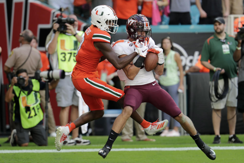 File-This Oct. 5, 2019, file photo shows Virginia Tech defensive back Caleb Farley, right, intercepting a pass intended for Miami wide receiver Dee Wiggins, left, during the first half of an NCAA college football game, in Miami Gardens, Fla. Farley was the first top prospect to make the decision that has added a whole new layer of uncertainty to the annual crapshoot that is the NFL draft. (AP Photo/Lynne Sladky, File)