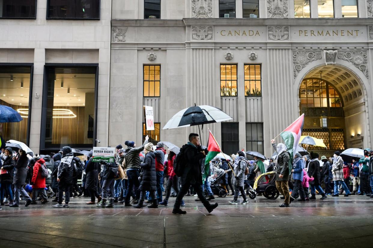 Demonstrators march as part of a rally in support of Palestinians in downtown Toronto on Dec. 23, 2023. Experts suggest the prosecution of a man charged with public incitement of hatred after allegedly waving a flag associated with the Popular Front for the Liberation of Palestine (PFLP) at a separate Toronto protest last weekend could be difficult based on Canadian laws.  (Christopher Katsarov/The Canadian Press - image credit)